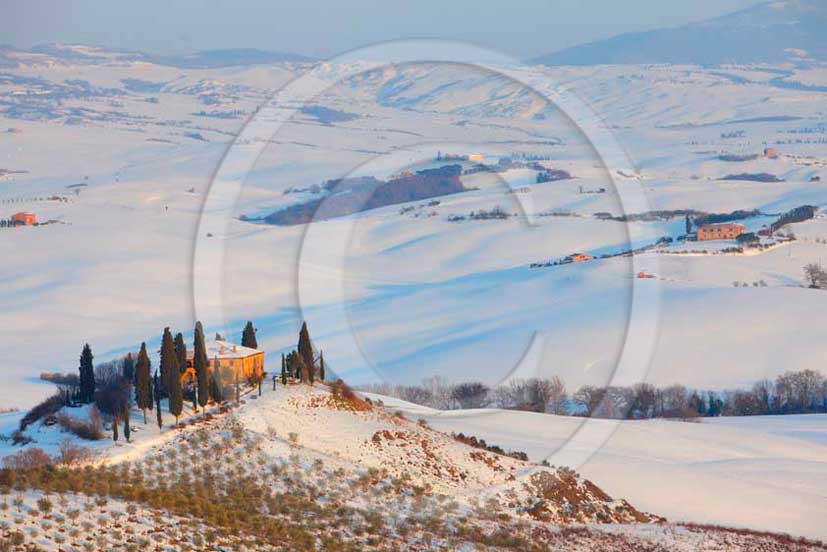 2012 - View of farm, cypress line with snow in winter in Orcia valley.