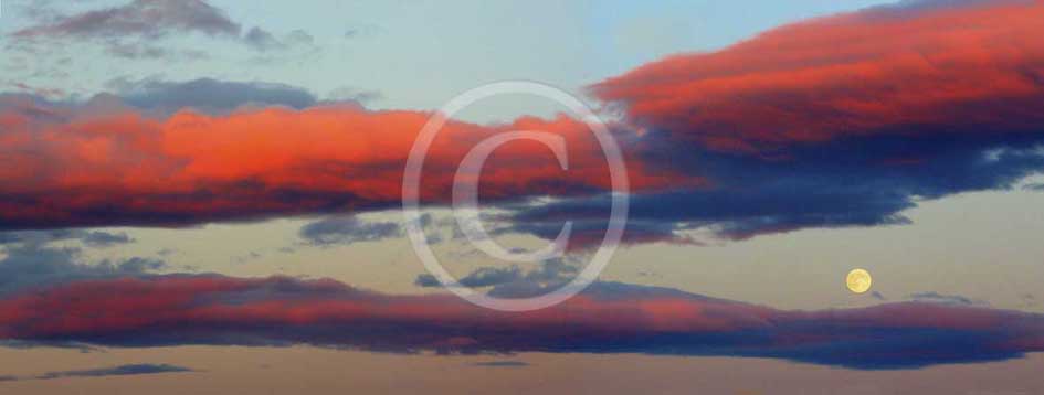 2013 - Panoramic view of orange, red and blue clouds with a full moon on summer.